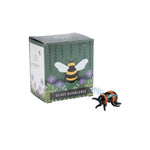 Artisan glass bumblebee figurine in front of its packaging box with bee design