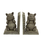 A pair of decorative bookends shaped like the Cheshire Cat, featuring a grey textured finish and a wide grin, inspired by lice in Wonderland books.