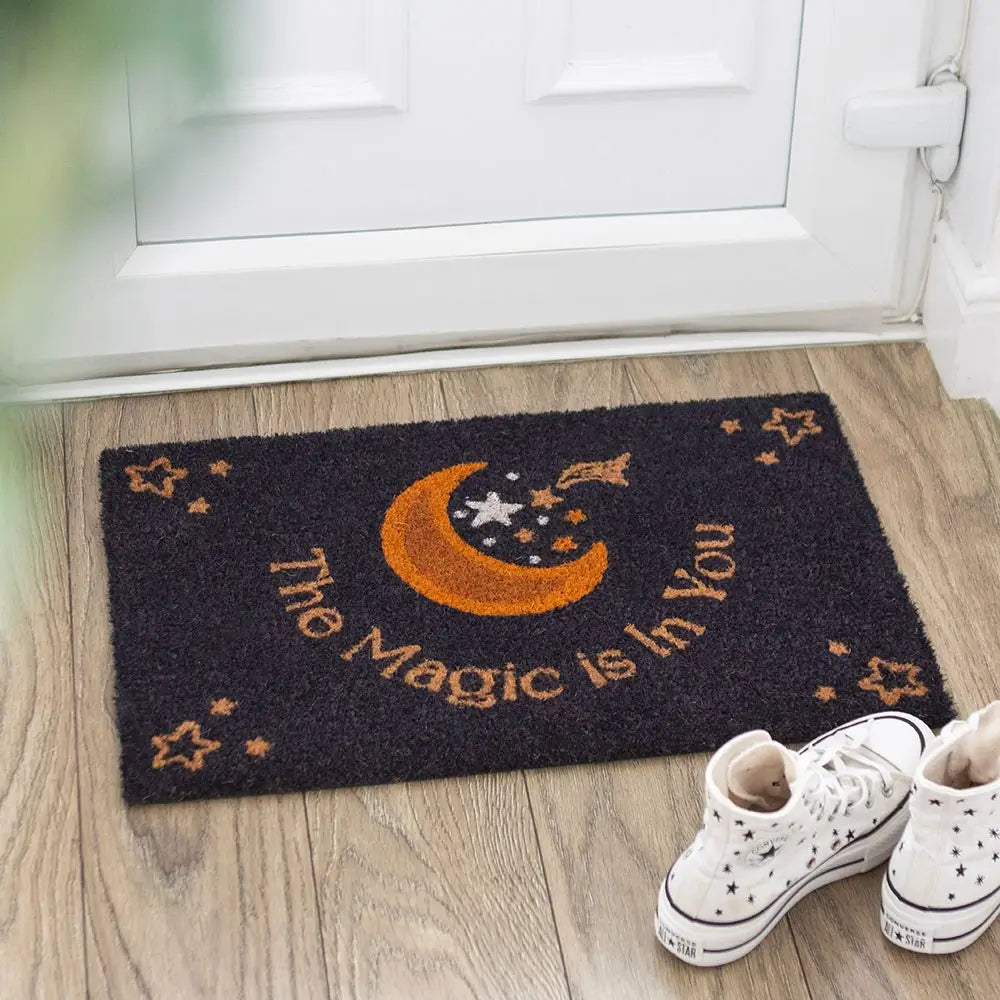 Decorative doormat with crescent moon and stars design and text 'The Magic is in You'.