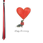 A square Five Dollar anniversary cardwith a watercolor illustration of a dachshund dog holding a large red heart, with the words 'Happy Anniversary' below. A red, black, and white ribbon is shown hanging along the left edge.