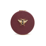 Round berry colour compact mirror with a bee emblem by Alice Wheeler London